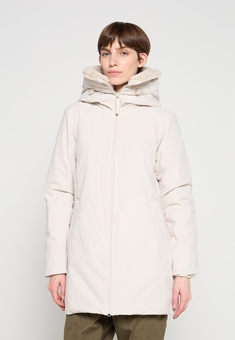 Leichte, cremefarbene Parka mit pelzgefütterter Kapuze, Frontreißverschluss und Seitentaschen. Strukturierter Stoff mit glatter Oberfläche.