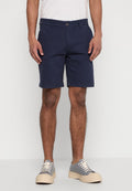Marineblaue Shorts mit geradem Schnitt aus gewobenem Baumwollstoff. Mit einem vorderen Knopfverschluss und seitlichen Taschen. Kombiniert mit grauen Sneakers.