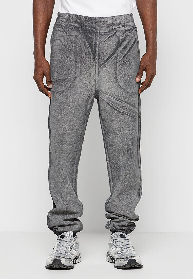 Graue Jogginghosen mit strukturiertem Finish, elastischem Bund und seitlichen Taschen. Am Knöchel schmal zulaufend, kombiniert mit silbernen Sneakers.
