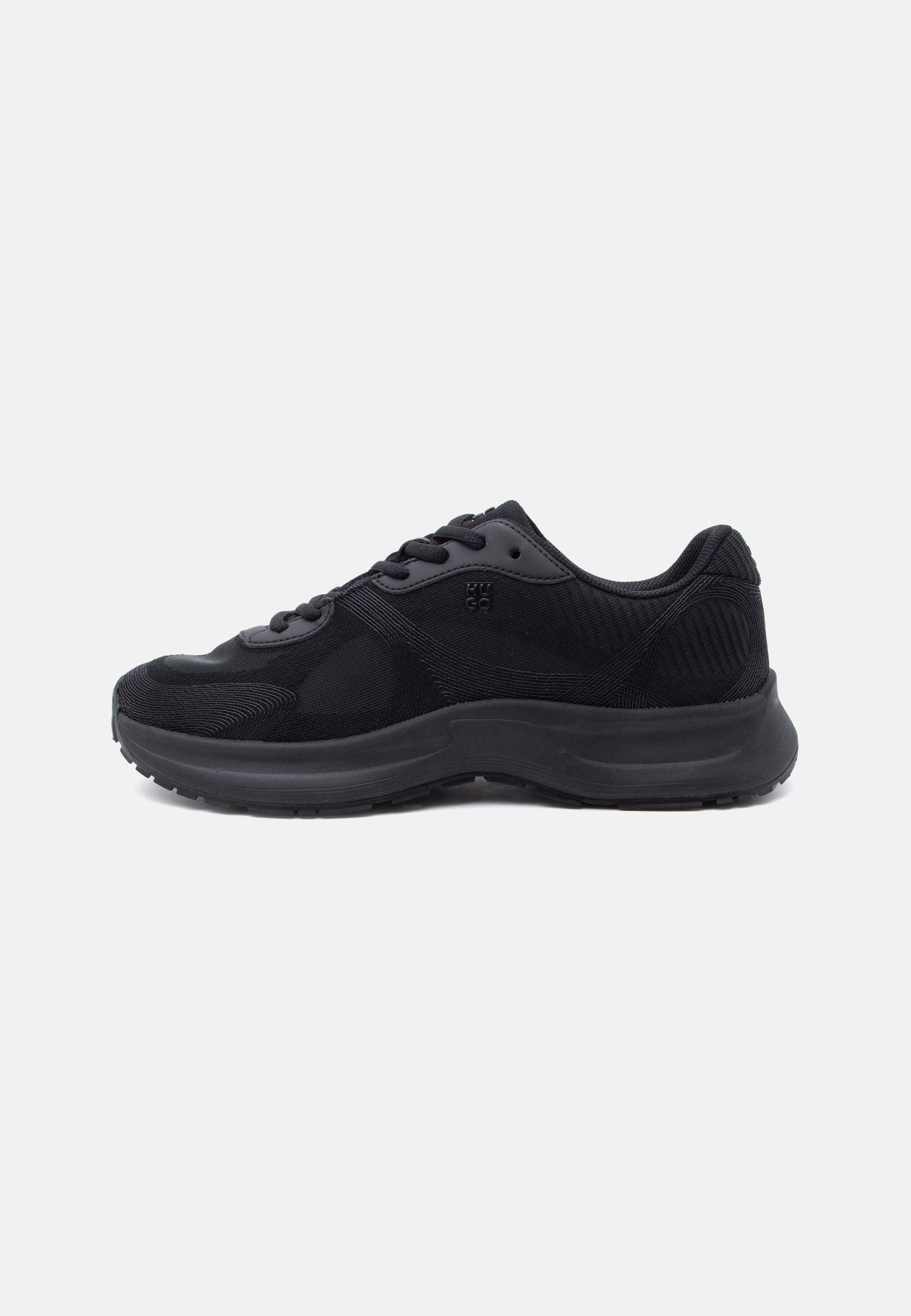 Schwarzer sportlicher Sneaker mit Mesh-Obermaterial, Schnürverschluss und dicker, gepolsterter Sohle, von der Innenseite auf weißem Hintergrund gezeigt.