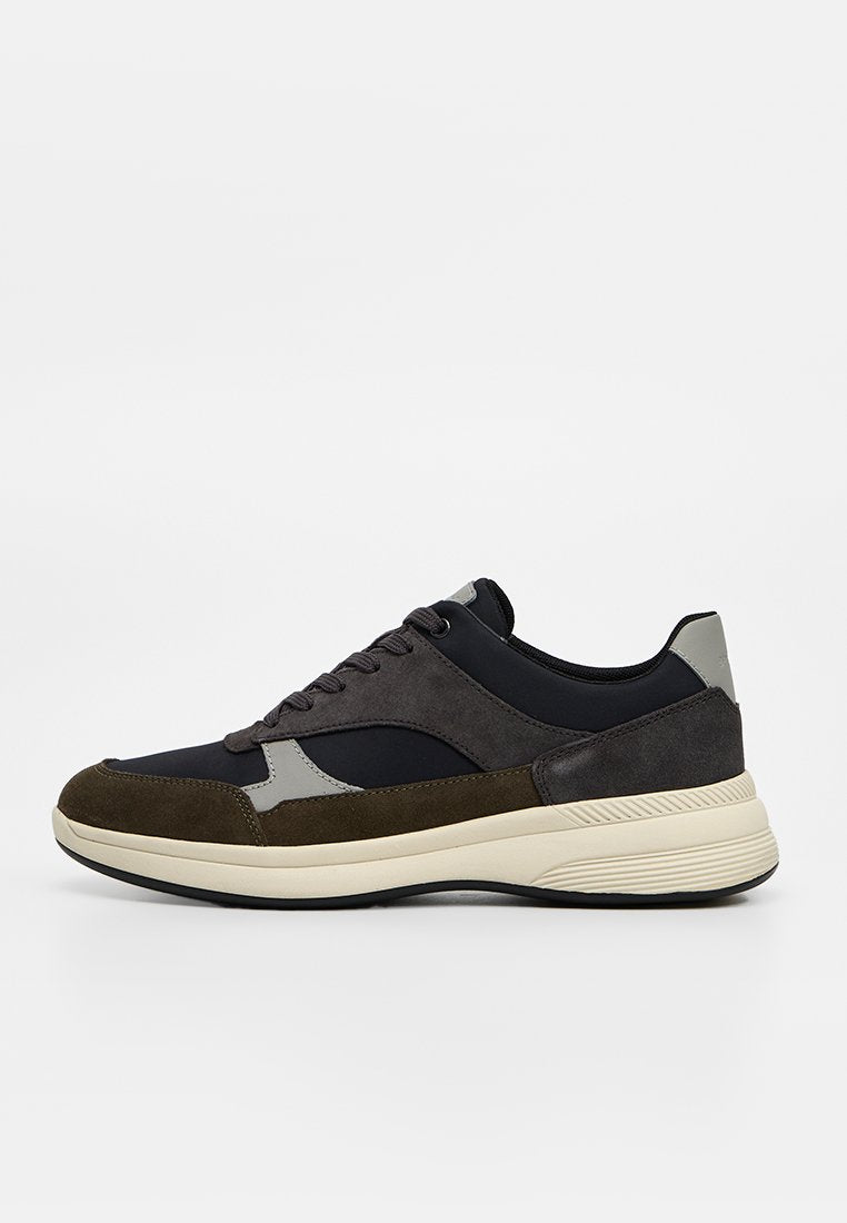Low-Top Sneaker mit schwarzem Stoff, dunkelgrauen und olivgrünen Wildledereinsätzen, beiger Sohle und schwarzen Schnürsenkeln auf weißem Hintergrund.