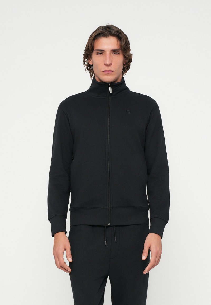 Schwarzer Sweatshirt mit Reißverschluss, hohem Kragen, gerippten Bündchen und Saum. Verfügt über ein dezentes Logo auf der Brust und ist aus einem weichen, strukturierten Stoff gefertigt.