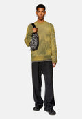 Gelber strukturierter Pullover mit Rippdesign, schwarze lässige Hose und eine schwarze Umhängetasche mit Grafik auf der Vorderseite.