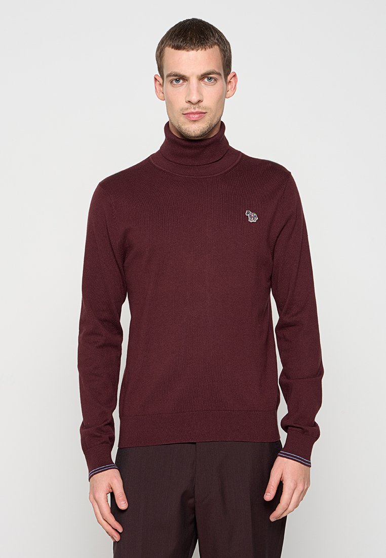 Bordeauxroter Rollkragenpullover in Rippenstrick, mit kleinem Logodetail auf der Brust und kontrastierenden, gestreiften Akzenten an den Bündchen.
