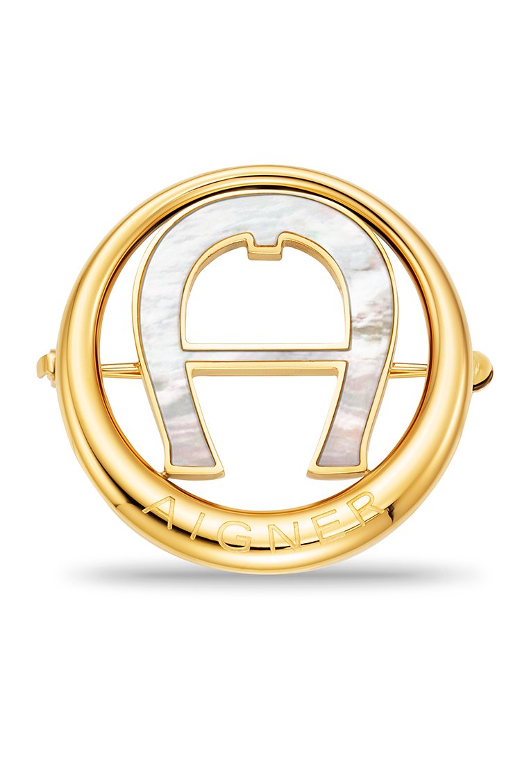 Goldfarbener Brosche mit einem runden Design, das ein perlisiertes "A"-Detail und den eingravierten Markennamen aufweist; glatte Metalloberfläche mit polierter Textur.