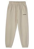 Beige Jogginghose mit einem elastischen Bund, zwei Seitentaschen und einem schwarzen "PEGADOR"-Logo, das auf dem linken Bein aufgedruckt ist. Glatte Stoffoberfläche.