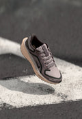 Hellblauer Sportschuh mit grauen Akzenten, mehrtexturiertes synthetisches Obermaterial, Schnürsenkel und eine beige Sohle mit sichtbarem Profil.