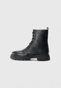 Schwarze Leder-Schnürstiefel im Combat-Stil mit dicker Profilsohle und Ziehlasche an der Ferse, seitlich auf einem schlichten Hintergrund dargestellt.