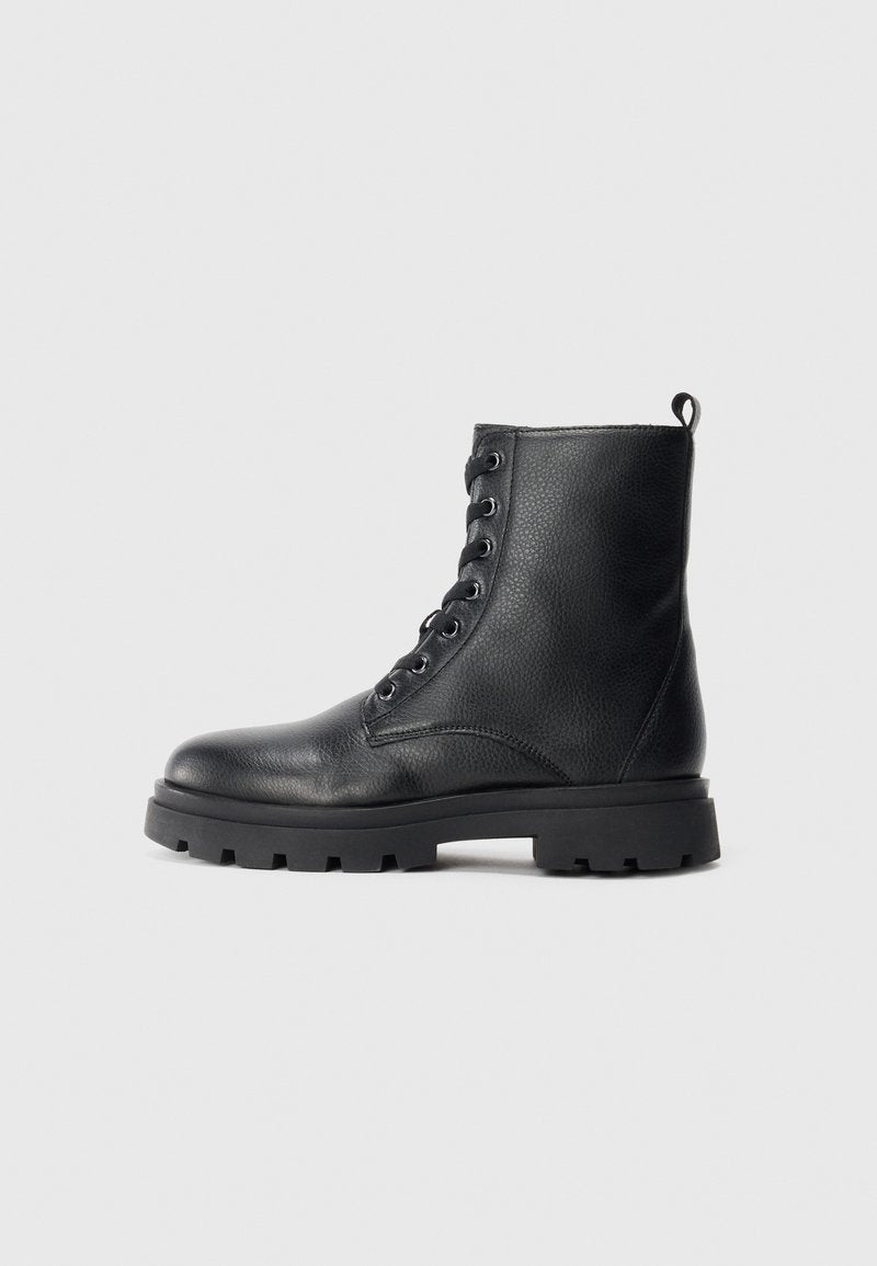 Schwarze Leder-Schnürstiefel im Combat-Stil mit dicker Profilsohle und Ziehlasche an der Ferse, seitlich auf einem schlichten Hintergrund dargestellt.