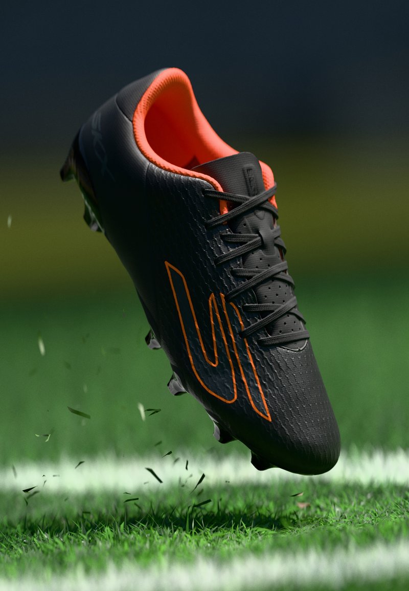 Schwarzer Fußballschuh mit orangefarbenen Akzenten, strukturiertem Obermaterial, Schnürsenkeln und Stollen. Er scheint über grünem Gras zu schweben.