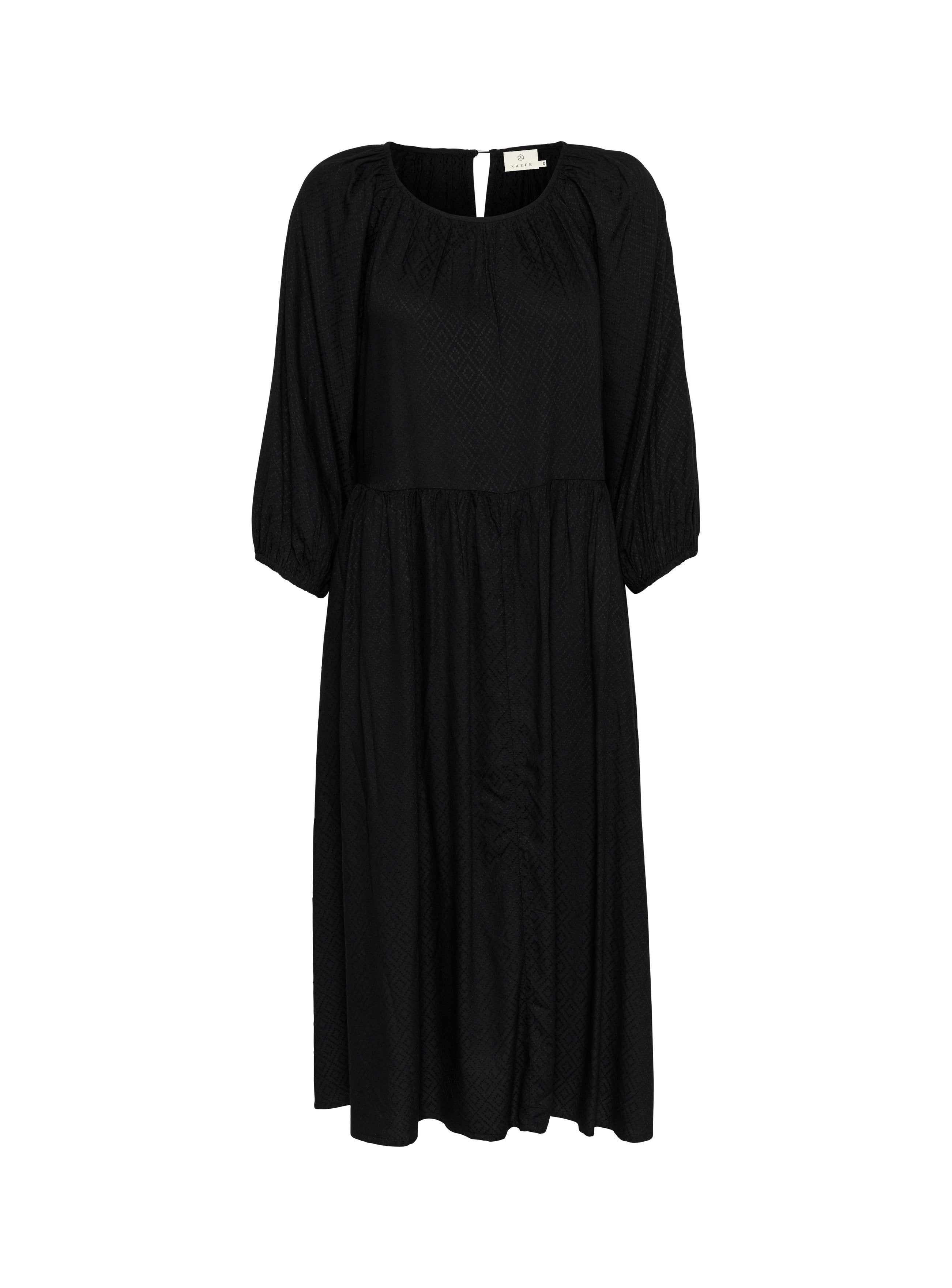 Schwarzes Kleid aus strukturiertem Stoff, mit rundem Ausschnitt, Puffärmeln und einem Schlüsselaugen-Detail am Rücken. Fließende A-Linie Silhouette.