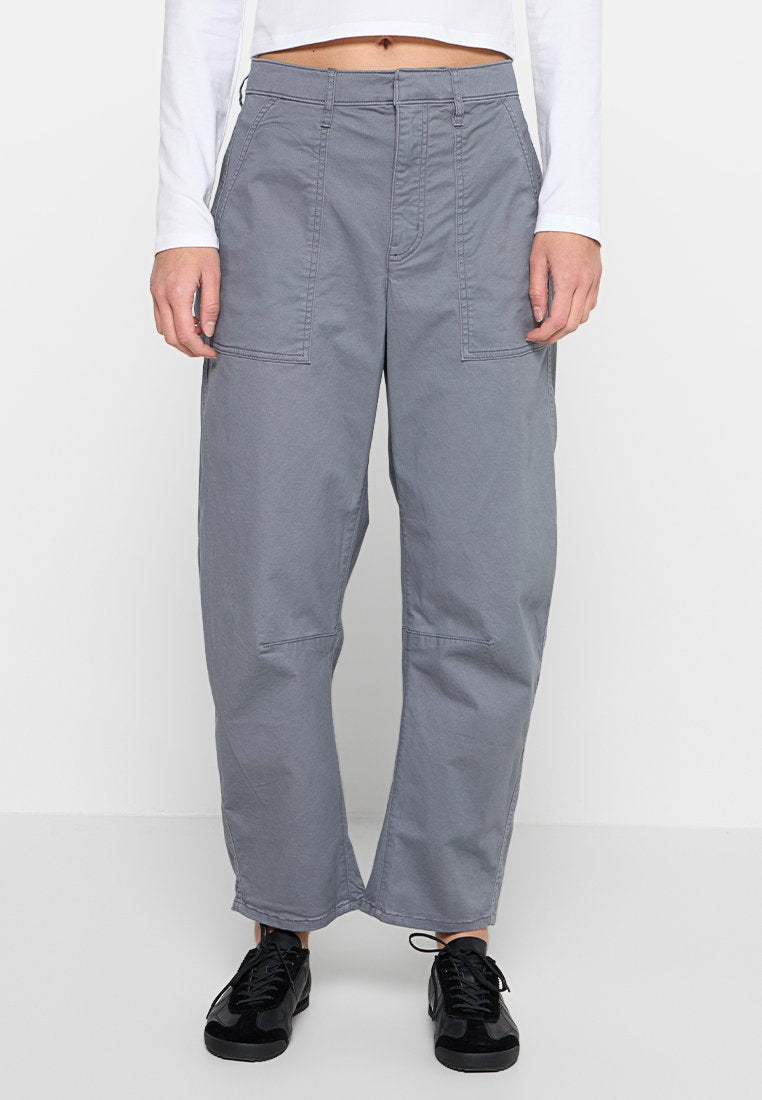 Graue Cargo-Hosen mit lockerer Passform, versehen mit Vordertaschen und einer glatten Textur, kombiniert mit schwarzen Sportschuhen.