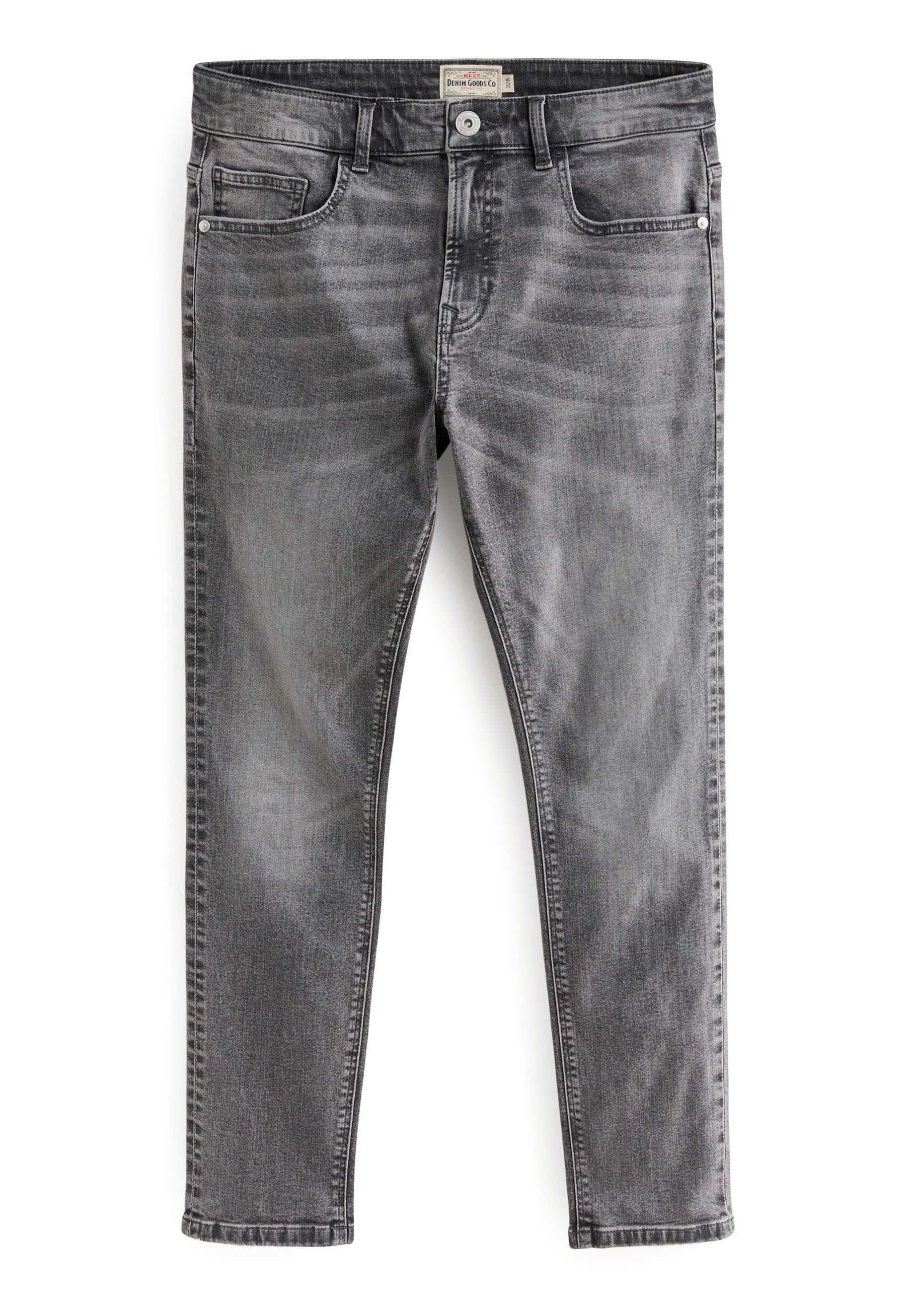 Schmal geschnittene, ausgebleichte graue Jeans mit frontalen Taschen, Gürtelschlaufen und Knopfverschluss, flach auf einem weißen Hintergrund ausgelegt.