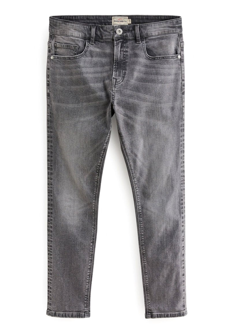Schmal geschnittene, ausgebleichte graue Jeans mit frontalen Taschen, Gürtelschlaufen und Knopfverschluss, flach auf einem weißen Hintergrund ausgelegt.