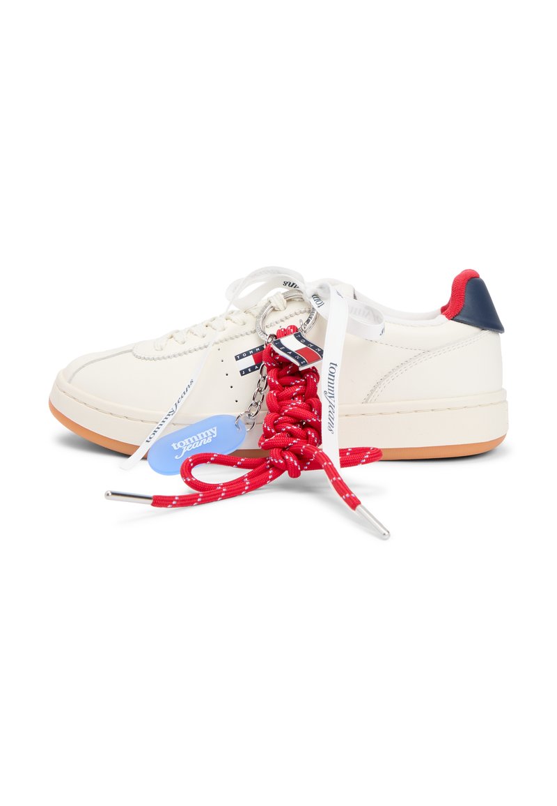 Weißer Low-Top-Sneaker mit blauen und roten Akzenten, weißen Schnürsenkeln mit Markenaufdruck und einem Schlüsselanhänger mit dicken roten Schnürsenkeln und einem blauen Tommy Jeans-Label.