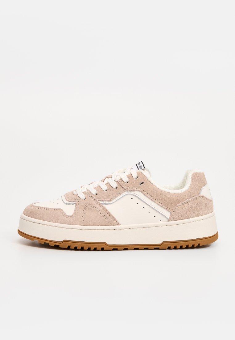 Niedriger Sneaker mit beigen Wildleder- und weißen Lederpaneelen, weißen Schnürsenkeln, gepolstertem Kragen und dicker weißer Sohle mit braun geriffelter Laufsohle.