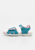 Blaue Kindersandale mit pinkfarbenen Blumenverzierungen, verstellbaren Riemen und einer gemusterten weißen Sohle, von der Seite vor schlichtem Hintergrund dargestellt.