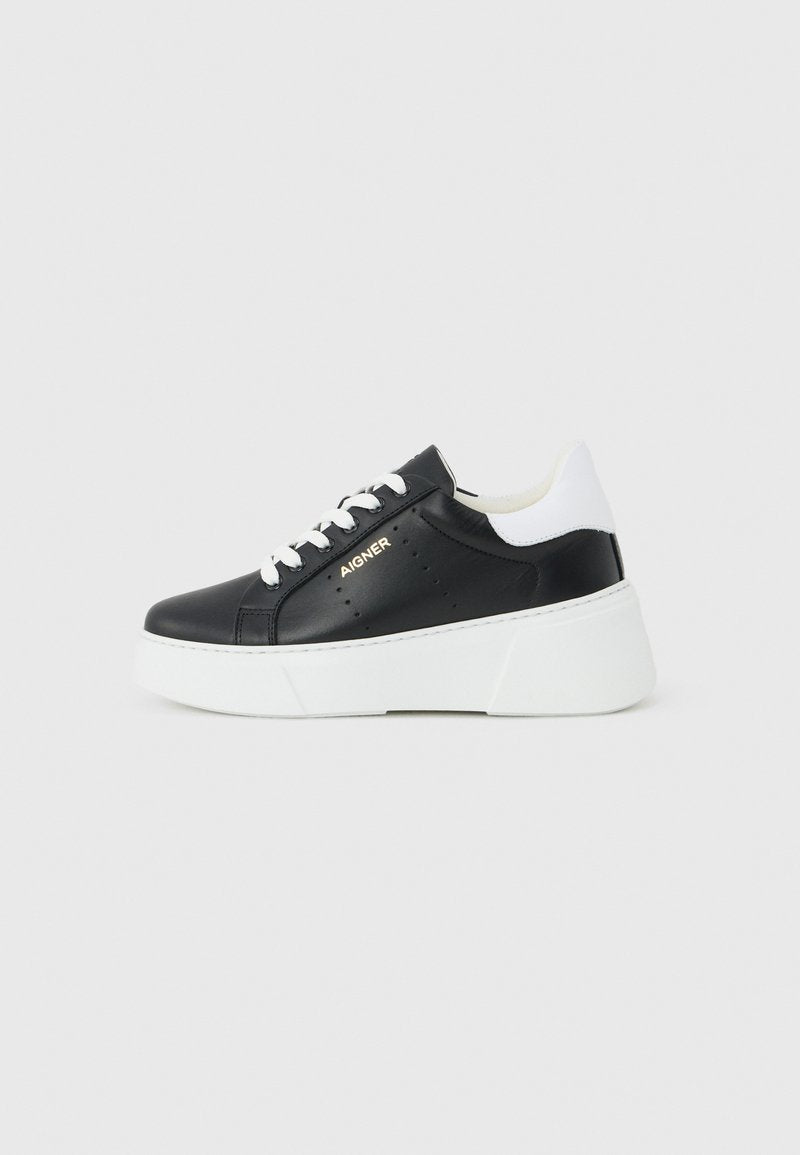 Schwarzer Sneaker mit weißen Schnürsenkeln und Ferse, dicker weißer Plateausohle und goldenem "AIGNER" Logo an der Seite.