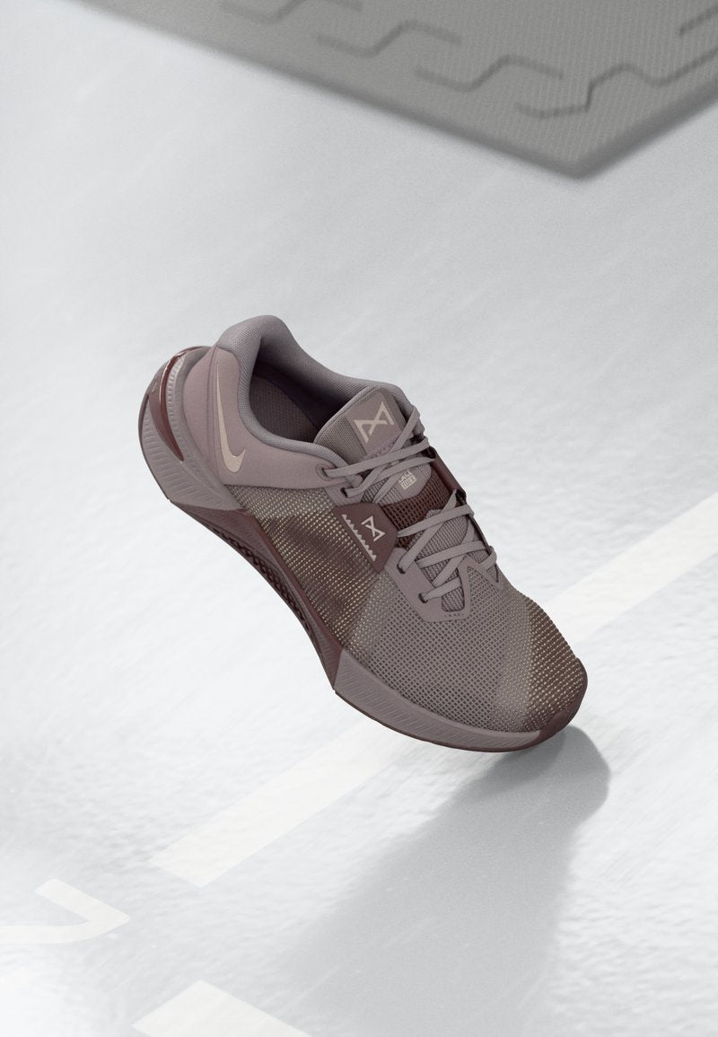 Hellgrauer Sportschuh aus Mesh- und synthetischen Materialien, mit einer strukturierten Sohle und runder Zehenpartie, akzentuiert durch dunklere Grautöne und ein Logo.