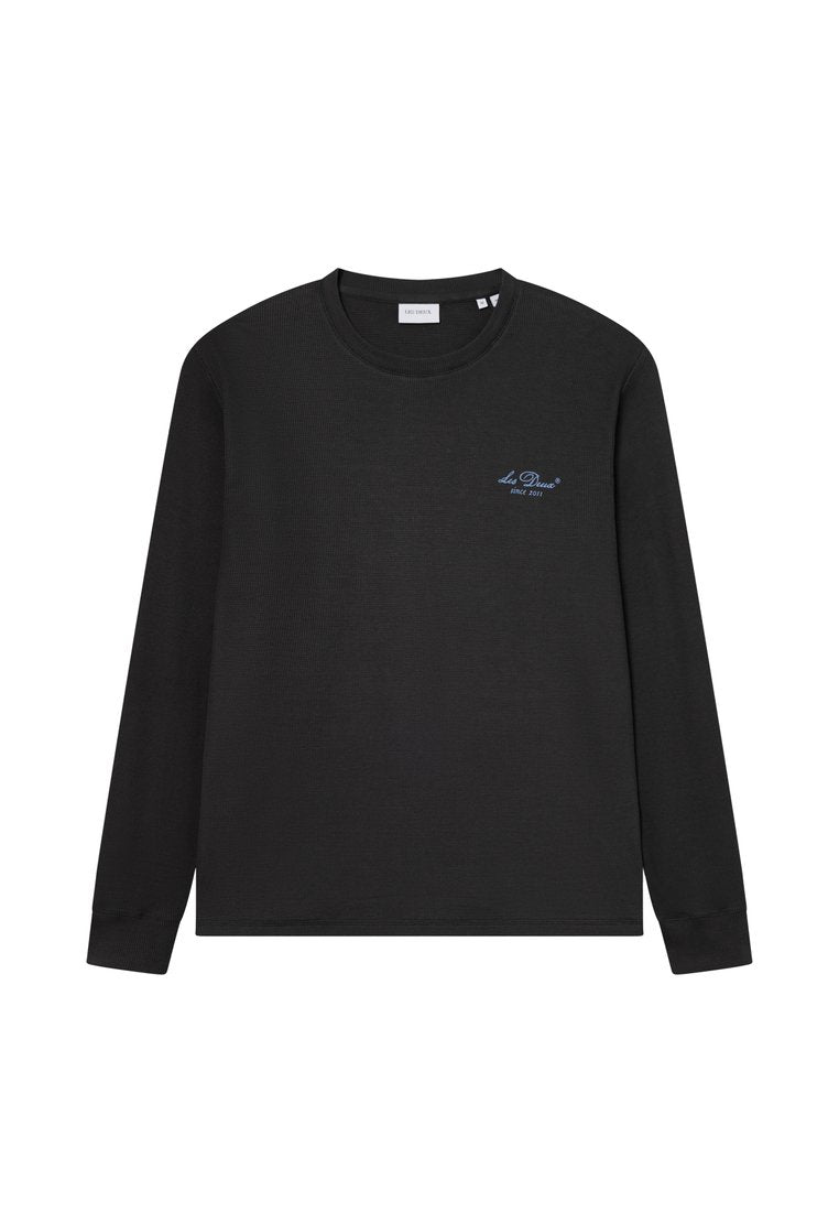 Langärmliges schwarzes Shirt aus geripptem Stoff mit rundem Ausschnitt. Verfügt über ein kleines blaues Logo auf der linken Brust und ein einfaches, klares Design.