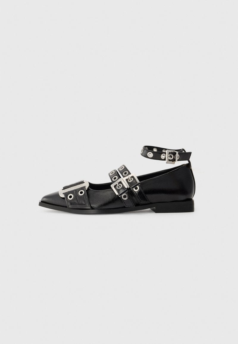 Schwarze spitz zulaufende flache Schuhe mit drei silbernen Riemen mit Schnallen, Knöchelriemen mit Ösen und metallischem Detail im Zehenbereich.