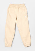 Beige Fleece-Jogginghose mit elastischem Bund, schmal zulaufenden Bündchen und kleinem weißem Logo auf der Vorderseite. Glatte Textur und lässige Passform.