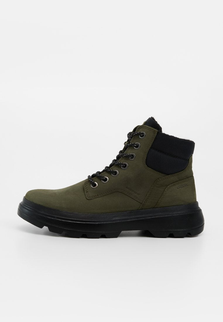 Olivgrüner hoher Stiefel mit schwarzem gepolstertem Knöchelkragen, schwarzen Schnürsenkeln und dicker schwarzer Gummisohle mit grobem Profil.