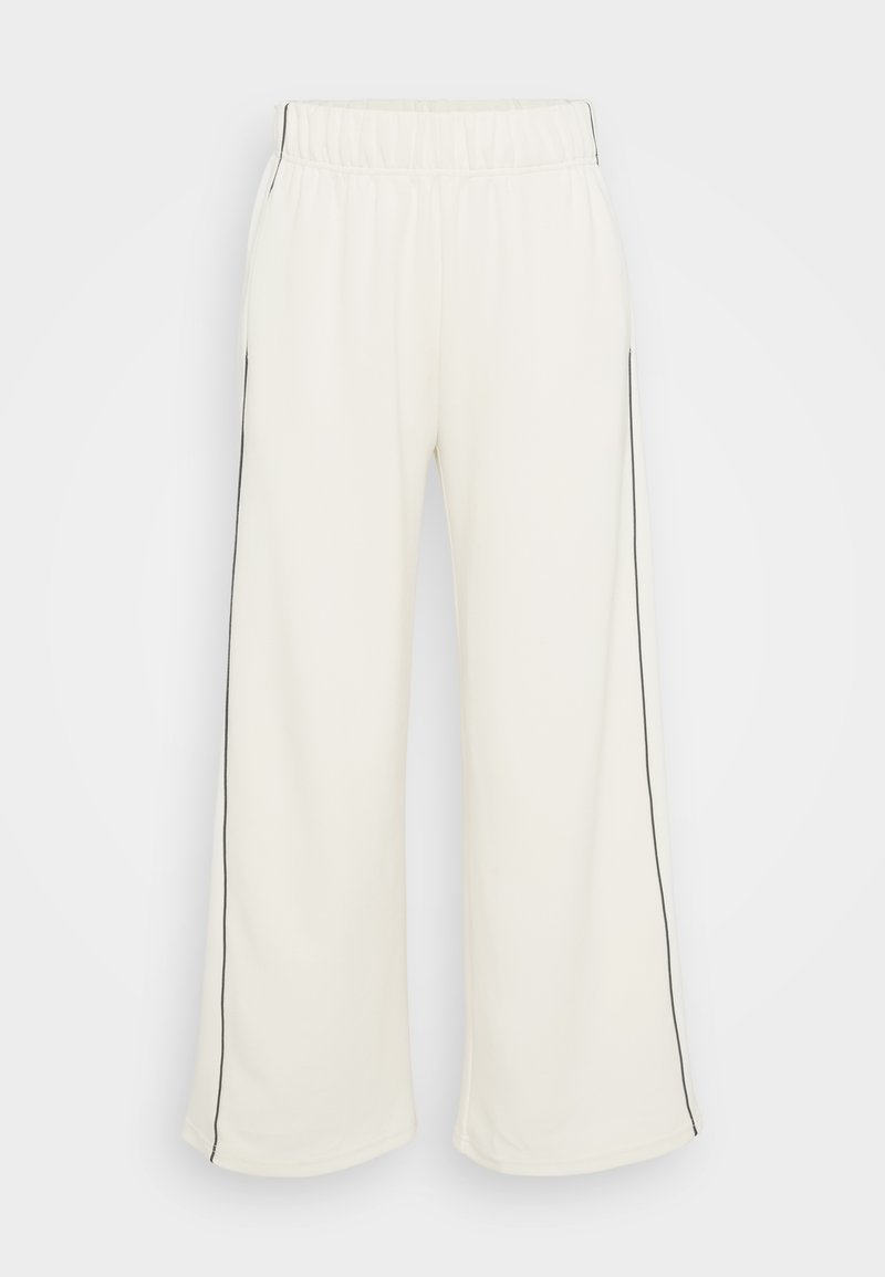 Weite Sweatpants in Creme mit einer weichen Textur, versehen mit schwarzen Seitenstreifen und einem elastischen Bund für Komfort und ein angenehmes Tragegefühl.