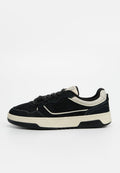 Schwarzer Veloursleder-Sneaker mit beigen Akzenten, runder Zehenpartie, flachen Schnürsenkeln und weißer Zwischensohle. Mit einem strukturierten Logo an der Seite.