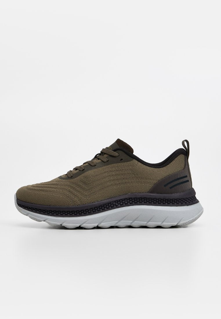 Sportlicher Schuh mit einem strukturierten olivgrünen Obermaterial, schwarzen Akzenten und einer gepolsterten grauen Sohle mit einem wellenartigen Design.