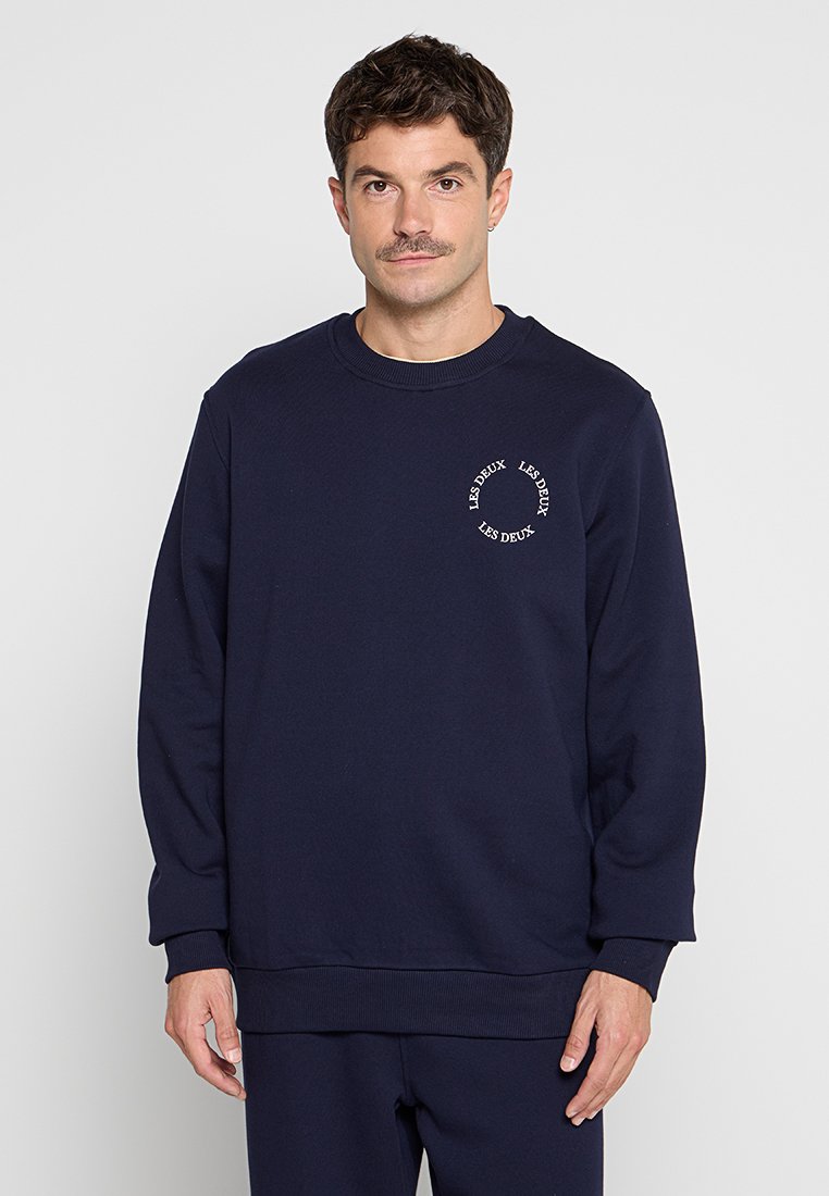 Dunkelblaues Sweatshirt aus Baumwollmischung mit gerippten Bündchen und Saum. Auf der Brust mit einem kreisförmigen Grafik-Text-Logo versehen. Schlichter Rundhalsausschnitt.