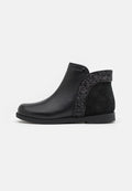 Schwarze Knöchelstiefel aus glattem Leder mit einem Wildlederrücken, die entlang der Seiten mit einem funkelnden schwarzen Glitzerakzent versehen sind und eine strukturierte Sohle haben.