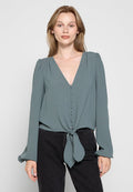 Tiefgrüne Langarm-Bluse mit tiefem V-Ausschnitt, Knopfverschluss vorne und gebundenem Knoten-Detail an der Taille. Weicher, leichter Stoff mit leichter Struktur.