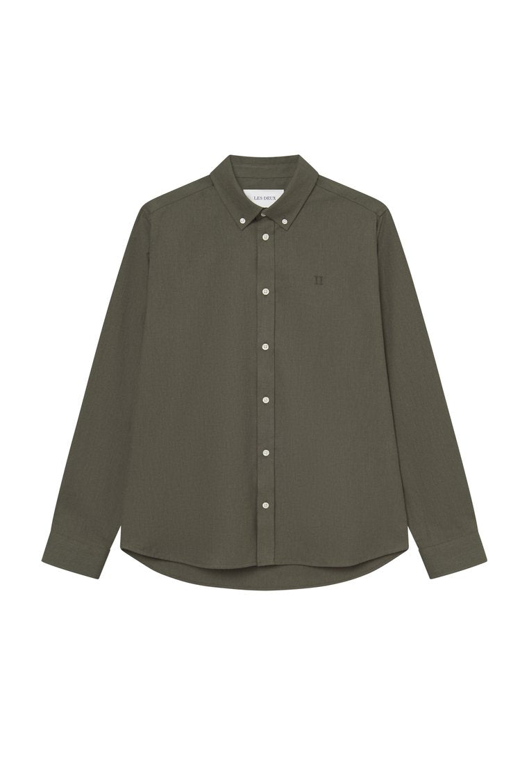 Olivegrünes Hemd mit Button-Down-Kragen, langen Ärmeln und abgerundetem Saum. Mit weißen Knöpfen und einem kleinen Logo auf der linken Brust.