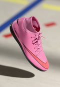 Rosa Nike Mercurial Fußballschuh mit schwarzen und roten Akzenten, ausgestattet mit einem glatten Synthetikobermaterial, flacher Sohle und Schnürdesign.