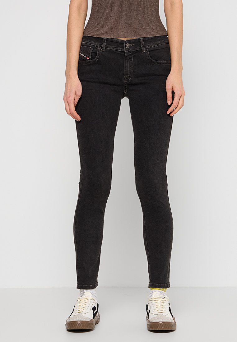 Schwarze schmale Jeans aus Denim, mit einem klassischen Fünf-Taschen-Design und dezenten Nähdetails. Kombiniert mit lässigen Sneakers.