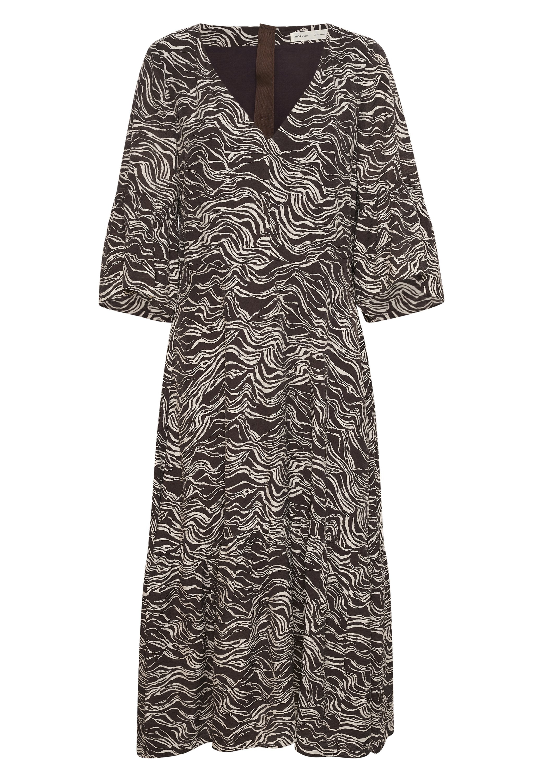 Schwarz-weißes Kleid mit wellenförmigem Muster, V-Ausschnitt und puffärmel, dazu ein gestuftes Rockteil und einem kontrastierenden schwarzen Taillenbund.