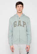 Junger Mann trägt eine hellblaue ZIP-Hoodie von GAP und graue Jogginghose mit GAP-Logo, steht vor einem schlichten Hintergrund.