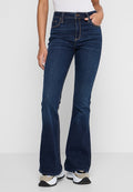 Dunkelblaue aufgerockte Jeans aus Denim mit sichtbaren Nähten. Hohe Taille und Fünf-Taschen-Design. Kombiniert mit weißen Sneakers.