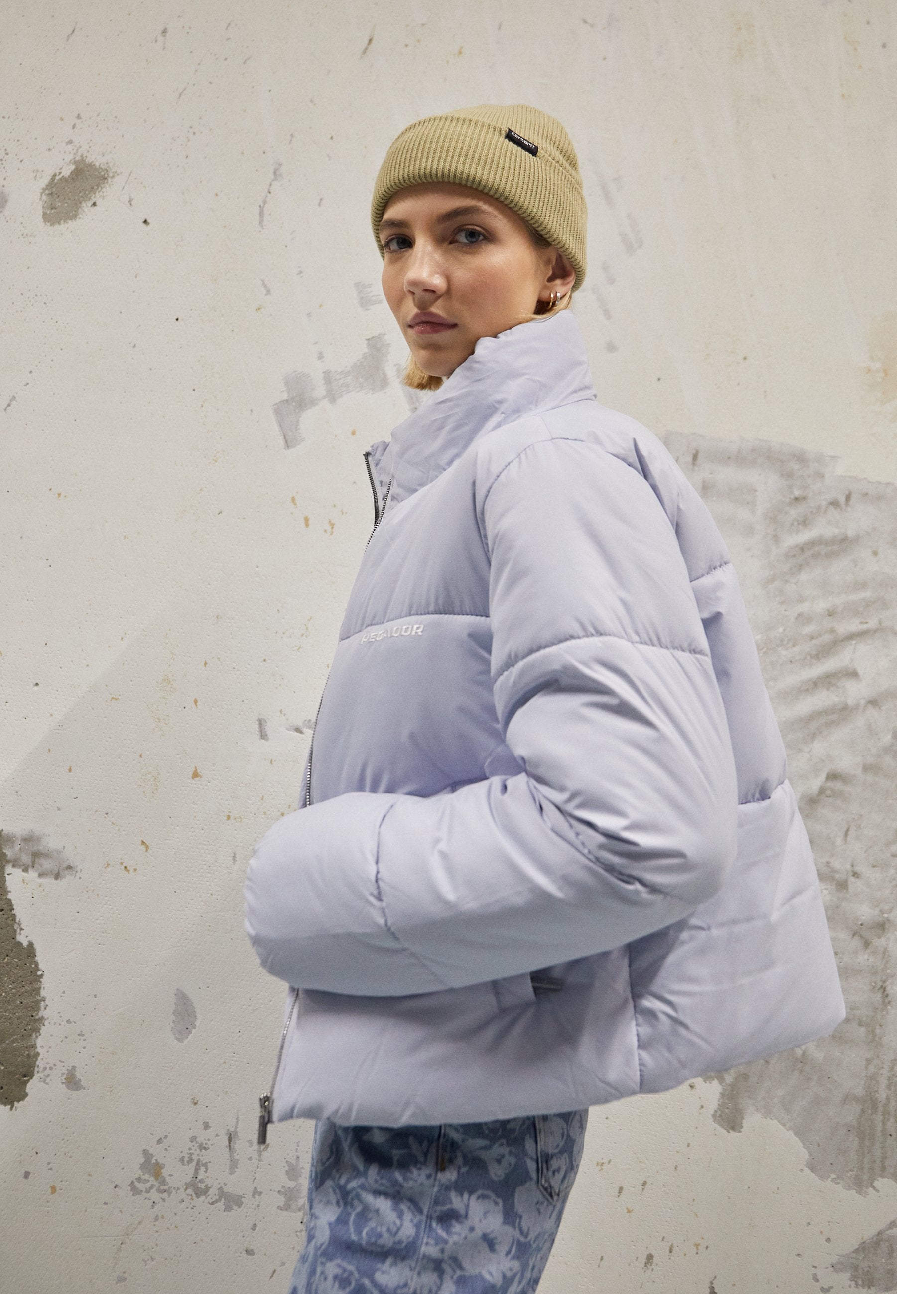 Helles lila Pufferjacke mit hohem Kragen und Reißverschluss, breiten Ärmeln und einer glatten, glänzenden Stoffoberfläche.