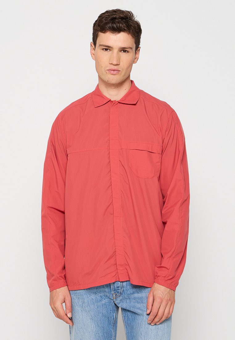 Hemd mit langen Ärmeln aus leichtem Korallengewebe, mit einem Button-Down-Kragen, einer einzelnen Brusttasche und einer lässigen Passform. Es hat eine leicht schimmernde Textur.