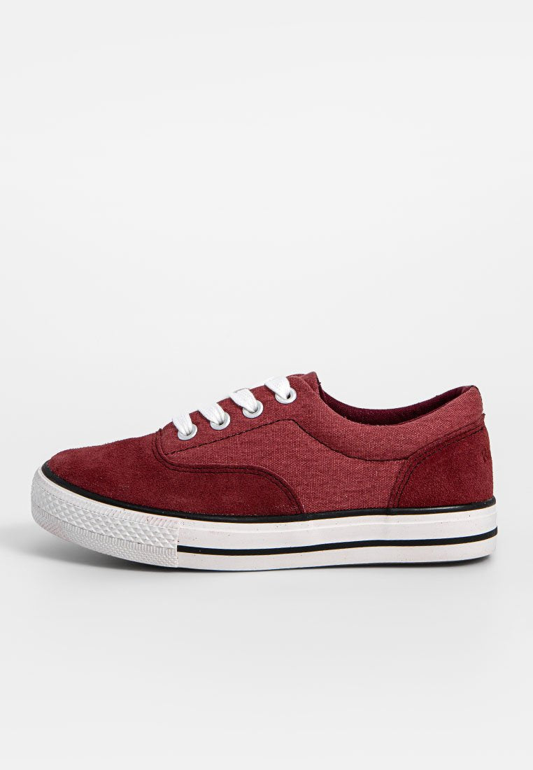 Burgunderfarbene Canvas-Sneaker mit Wildlederakzenten, weißen Schnürsenkeln und einer Gummisohle, die entlang des Randes schwarze Streifen aufweist. Klassisches, rundes Zehendesign.