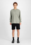Langärmliges olivgrünes Hemd kombiniert mit schwarzen Shorts, getragen mit schwarzen Socken und schwarzen Slippern. Einfaches, entspanntes Design ohne Muster.