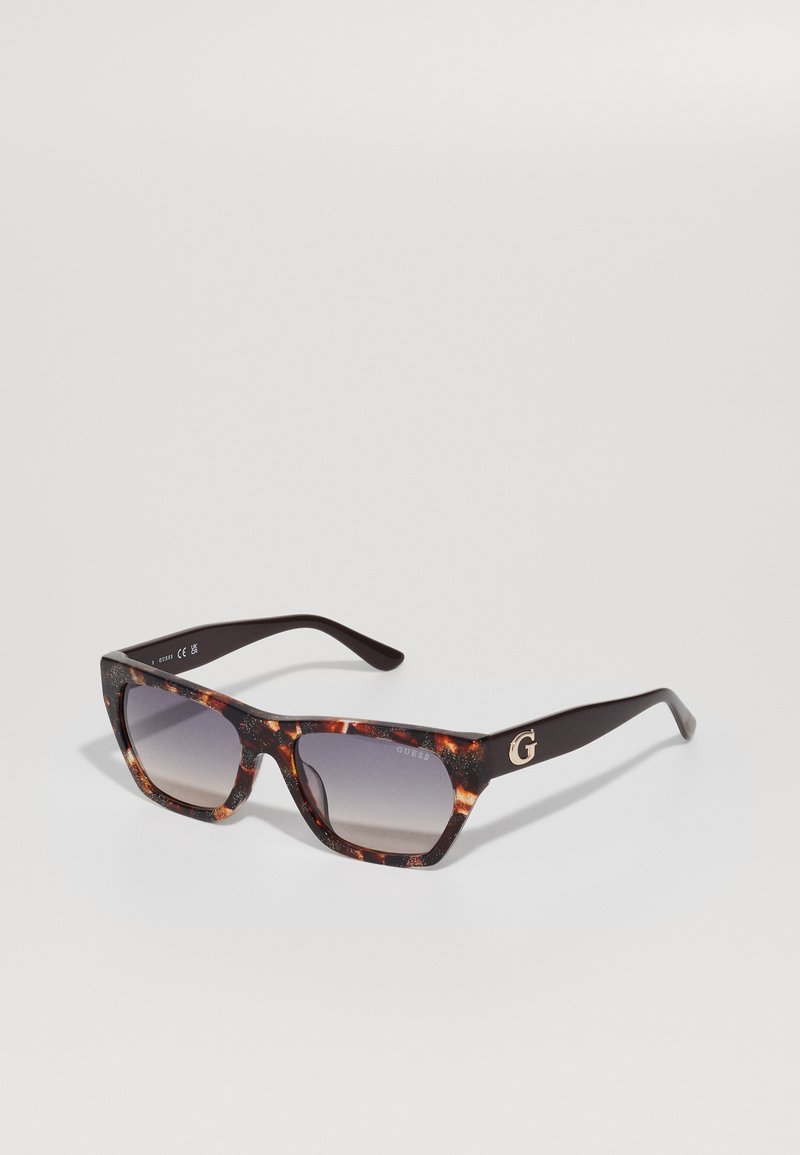 Sonnenbrille mit tortoise-farbenem Rahmen, Verlaufsgläsern und einem dunkelbraunen, festen Bügel mit einem goldenen "G"-Logo.