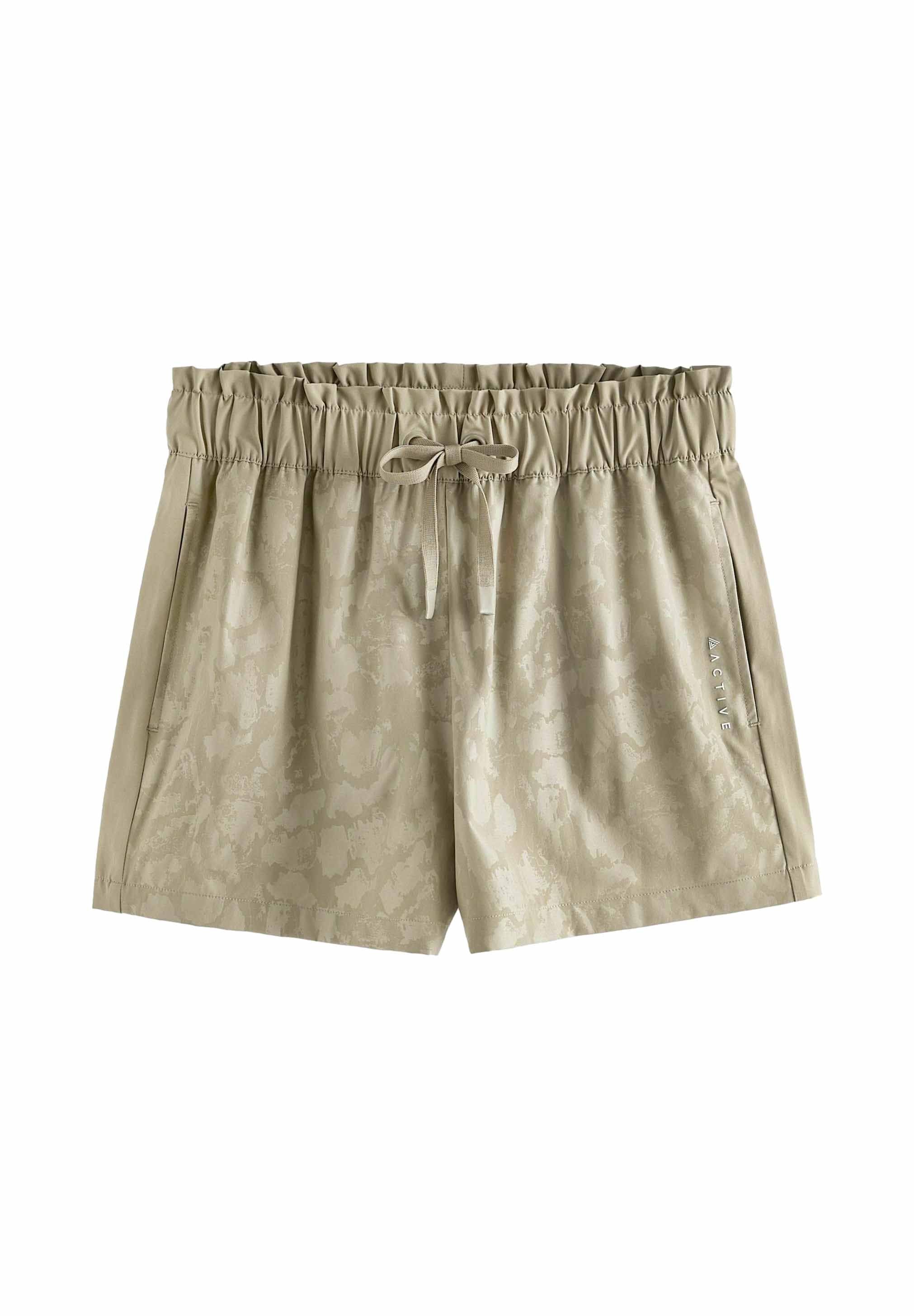 Beige Shorts mit elastischem Bund, Kordelzug und Seitentaschen. Sie verfügen über ein dezentes Muster und das Wort "ACTIVE" auf einer Seite aufgedruckt.