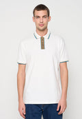 Weißes Poloshirt aus Baumwolle mit einem mehrfarbig gestreiften Kragen und Knöpfen. Kurze Ärmel mit kontrastierenden Akzenten. Kombiniert mit blauen Jeans.