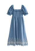 Blaues, rüschenschürzendes Kleid mit quadratischem Ausschnitt und Puffärmeln. Mit floraler Bestickung am Saum und einem fließenden, leichten Stoff.