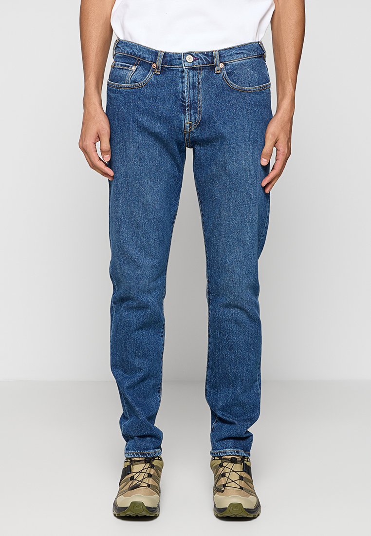 Blaue Jeans aus Denim mit geradem Schnitt, mit Kontrastnähten, fünf Taschen und metallischem Knopfverschluss. Stylisch kombiniert mit Schuhen in neutralen Farben.