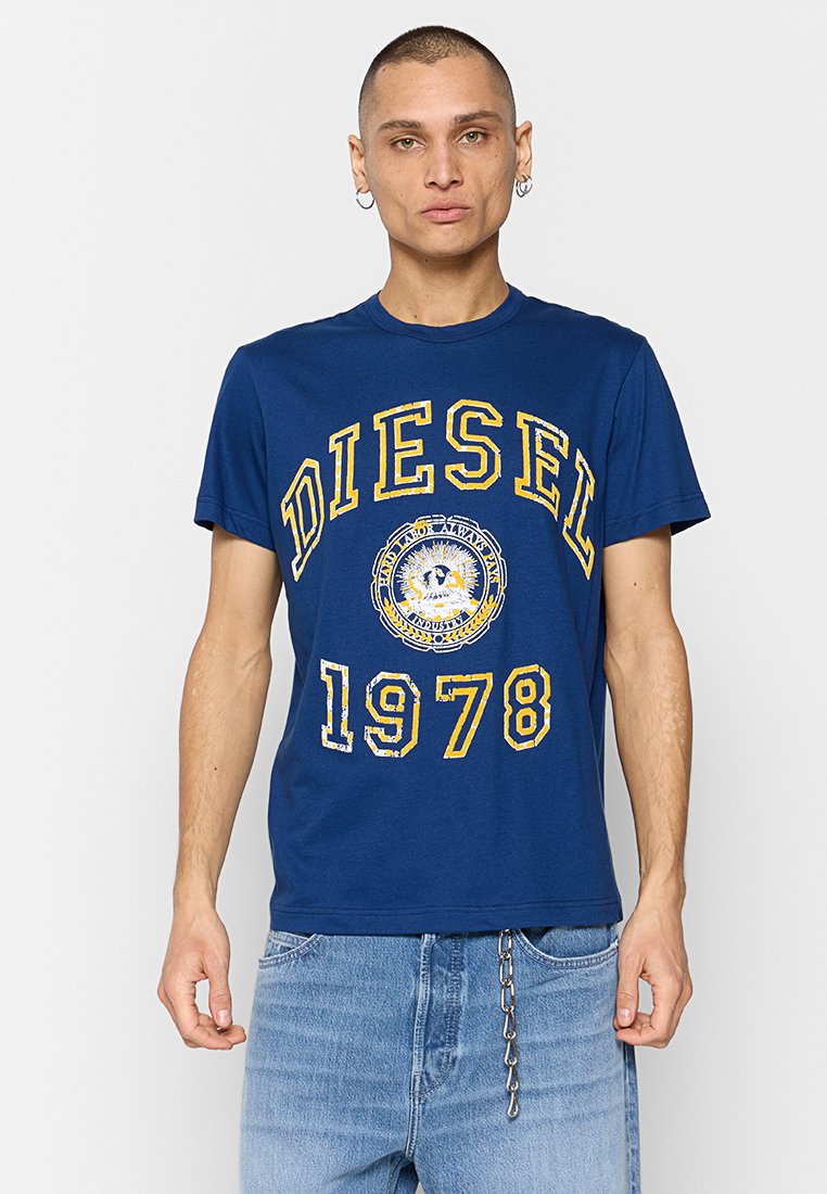 Marineblaue Baumwoll-T-Shirt mit auffälligem gelbem "DIESEL"-Logo und "1978" in distressed Druck. Kurze Ärmel, runder Ausschnitt und lockere Passform.