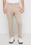 Beige Hose mit geradem Bein, ausgestattet mit einem Knopfverschluss und gesticktem Logo-Detail auf der linken Seite. Kombiniert mit weißen Sneakern.
